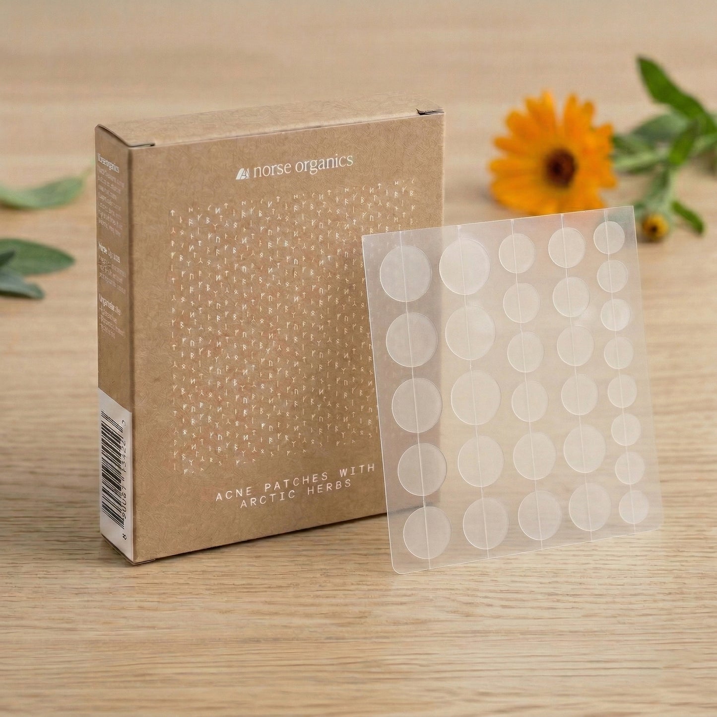 Norse Organics Acne Patches box and patch sheet on wood beside a calendula flower